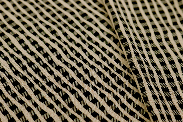 ベージュ地のよろけ格子柄ストレッチニット生地の斜めアップ